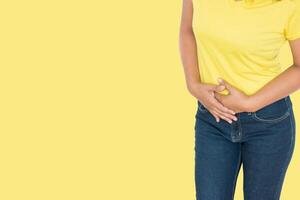 Woman stomach ache health care concept on yellow background photo