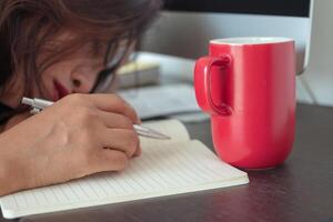 very sleepy and tired business woman on desktop computer, red coffee mug. photo