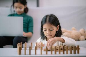 A girl is playing with wooden blocks on a table photo