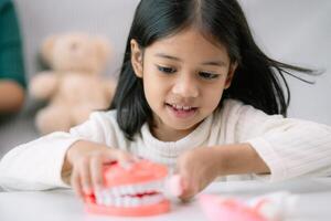 A young girl is playing with a toy toothbrush and a toy tooth photo