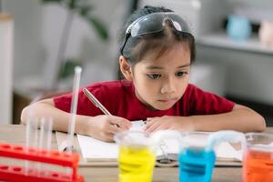 Asian girl making Walking Water experiment. Food color is added to the water in the glass, water moves along the paper, and then color is mixed. Concept of science for kid photo