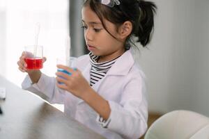 asiático niño niña aprendizaje Ciencias química con prueba tubo haciendo experimentar a colegio laboratorio. educación, ciencia, química, y para niños conceptos. temprano desarrollo de niños. foto