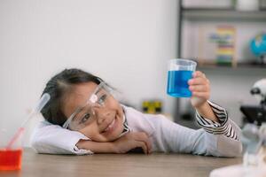 asiático niño niña aprendizaje Ciencias química con prueba tubo haciendo experimentar a colegio laboratorio. educación, ciencia, química, y para niños conceptos. temprano desarrollo de niños. foto