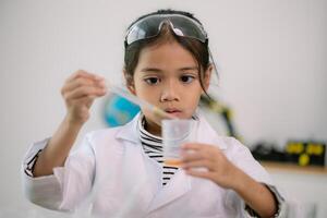 asiático niño niña aprendizaje Ciencias química con prueba tubo haciendo experimentar a colegio laboratorio. educación, ciencia, química, y para niños conceptos. temprano desarrollo de niños. foto