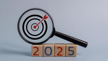 A magnifying glass is on top of a pile of wooden blocks with the number 2025 on photo