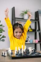 un joven niña en un amarillo camisa es jugando un juego de ajedrez foto
