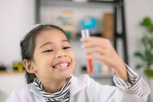 asiático niño niña aprendizaje Ciencias química con prueba tubo haciendo experimentar a colegio laboratorio. educación, ciencia, química, y para niños conceptos. temprano desarrollo de niños. foto