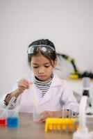 asiático niño niña aprendizaje Ciencias química con prueba tubo haciendo experimentar a colegio laboratorio. educación, ciencia, química, y para niños conceptos. temprano desarrollo de niños. foto