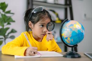A young girl is looking at a globe with a magnifying glass photo
