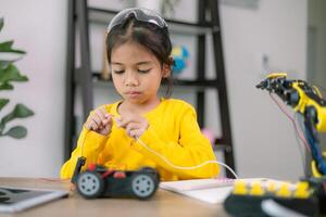 A young girl is working on a robot in a yellow shirt photo