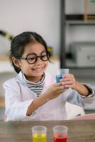 Little cute girl with a microscope holding a laboratory bottle with water experiment study scientists at school. Education science concept. photo