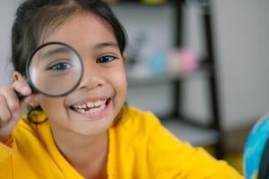 A young girl is holding a magnifying glass and smiling photo