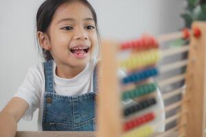 linda asiático niño niña aprendizaje a contar utilizando un ábaco en el salón de clases a jardín de infancia. foto