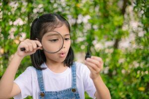 A young girl is holding a magnifying glass and looking at something photo