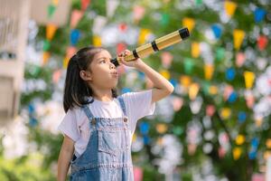 A young girl is looking through a telescope photo