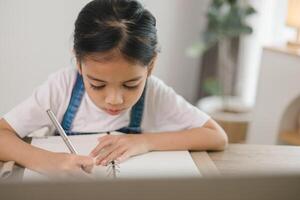 un joven niña es escritura en un cuaderno foto