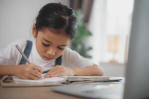 un joven niña es escritura en un cuaderno foto