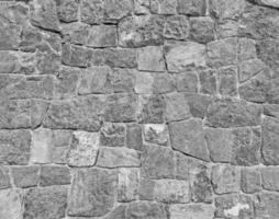 Gray stone wall background with copy space in monochrome tone. Grey rock block or tile wallpaper in loft style. Exterior design and pattern in black and white tone. photo