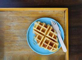 Top view of waffle topped with honey sauce on blue plate at cafe. Flat lay of Sweet bakery on dish with copy space. photo