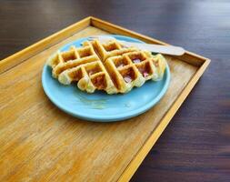 Waffle topped with honey sauce on blue plate at cafe. Sweet bakery on dish with copy space. photo