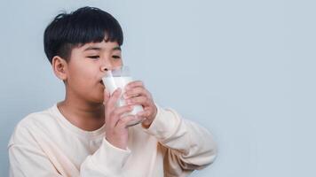 concepto de contento bueno nutrición, retrato de un pequeño joven hermoso niño chico en crema color camisa, sostener Bebiendo Leche caja Bosquejo, aislado en blanco antecedentes. foto