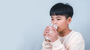 concepto de contento bueno nutrición, retrato de un pequeño joven hermoso niño chico en crema color camisa, sostener Bebiendo Leche caja Bosquejo, aislado en blanco antecedentes. foto