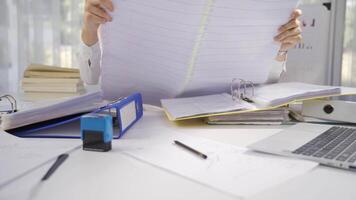 Businessman works at his desk, looks at big table of projects and plans. video