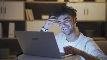 Young man using laptop at home at night. video