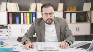 Stressed businessman looks at charts. video