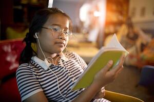 asiático niña leyendo colegio libro en hogar viviendo habitación foto