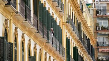 malaga, Spagna, 2018 - anziano uomo fumo un' tubo su un' balcone di un' Casa nel il vecchio cittadina di malaga video