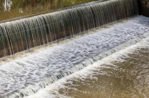 A background view of a violent flood flowing across a concrete dam and spillway. photo