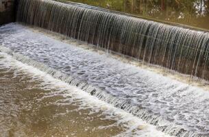 A background view of a violent flood flowing across a concrete dam and spillway. photo