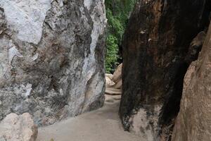 Pathway in the rock. At Wat Tham Khao Bot Tample Wangchan Rayong Thailand. The path between the rocks. photo