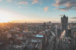 acecho el puesta de sol terminado Gante desde el histórico torre en el ciudad centro. romántico colores en el cielo. rojo ligero esclarecedor gante, flandes región, Bélgica foto