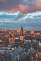 acecho el puesta de sol terminado Gante desde el histórico torre en el ciudad centro. romántico colores en el cielo. rojo ligero esclarecedor gante, flandes región, Bélgica foto