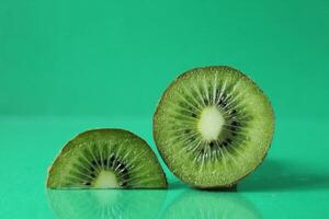 half and a circle of kiwi kusrchek with reflection on a green background with a copyspace photo