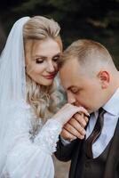 el novio Besos el de la novia mano. Boda foto de un Pareja en amor. un joven y hermoso hombre besos su de la esposa mano con un oro anillo, proponiendo.