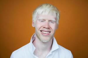 portrait of an albino man in studio dressed t-shirt isolated on a yellow background. abnormal deviations. unusual appearance photo