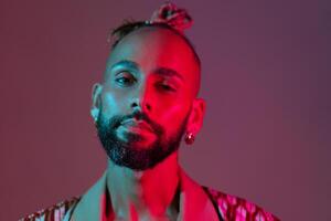 Neon light studio close-up portrait handsome black gay man looking camera. photo