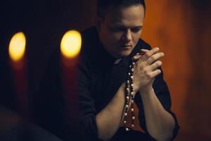 Praying priest. Portrait of priest Next to the candles prays photo