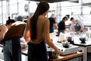 Culinary class. Back view of the process of cooking. Different unrecognizable people in gray apronsthe in the kitchen learn to cook photo