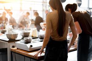 Culinary class. Back view of the process of cooking. Different unrecognizable people in gray apronsthe in the kitchen learn to cook photo