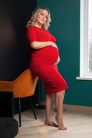 Pregnant Woman Posing In An Elegantred Dress indoors studio black wall background photo