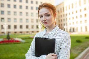 hermosa rojo peludo niña con pecas abrazando cuadernos con deberes y sonriente contento. espalda a colegio concepto. retrato de un estudiante foto