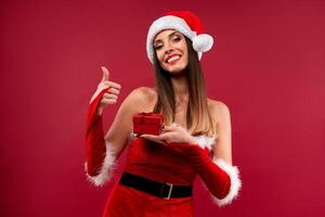 cerca arriba retrato hermoso caucásico mujer en rojo Papa Noel sombrero en rojo estudio antecedentes. Navidad y nuevo año fiesta concepto. foto