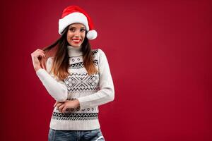 Close up portrait beautifiul caucasian woman in red Santa hat on red studio background. Christmas and New Year holiday concept. photo