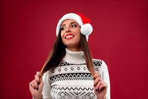 cerca arriba retrato hermoso caucásico mujer en rojo Papa Noel sombrero en rojo estudio antecedentes. Navidad y nuevo año fiesta concepto. foto