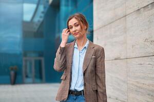 mujer de negocios exitoso mujer negocio persona en pie al aire libre corporativo edificio exterior. pensativo caucásico confianza profesional negocio mujer medio años foto