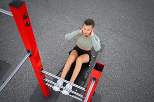 Sit-ups exercises. Active, fit sporty woman doing situps, exercising and training for fitness outdoor gym photo